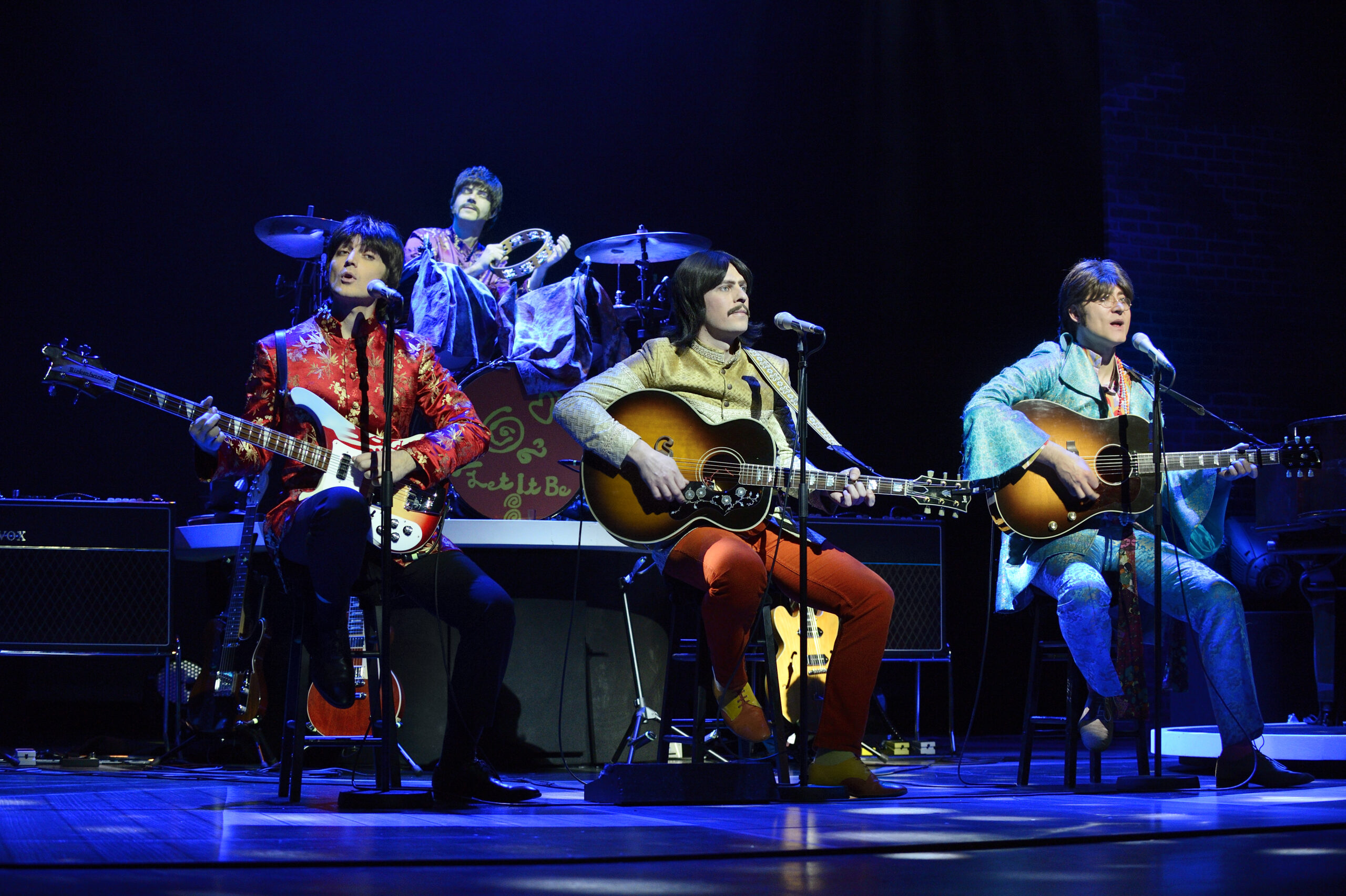 "Let It Be" cast members dressed as The Beatles during the Sergeant era on stage.