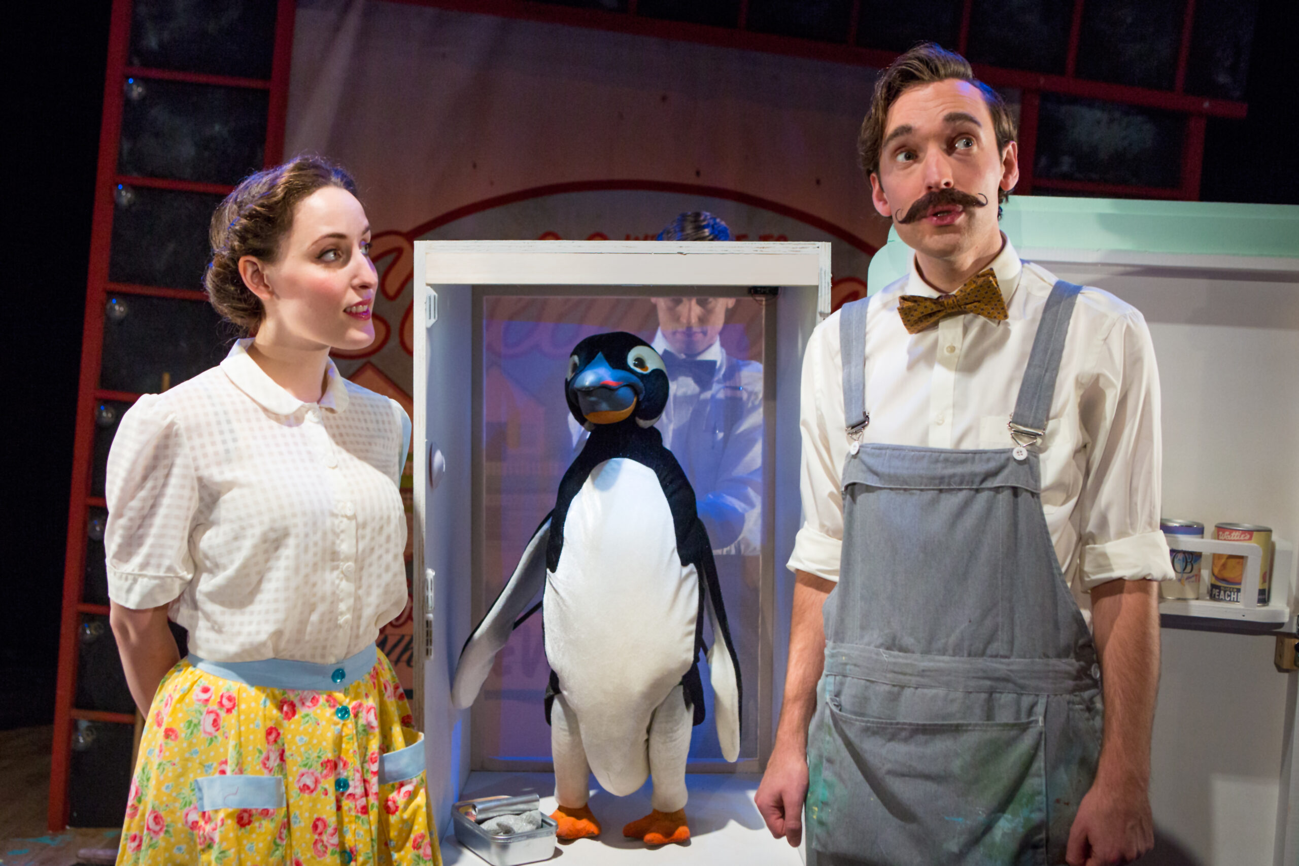 Mr. Popper and his wife on stage with a penguin puppet.