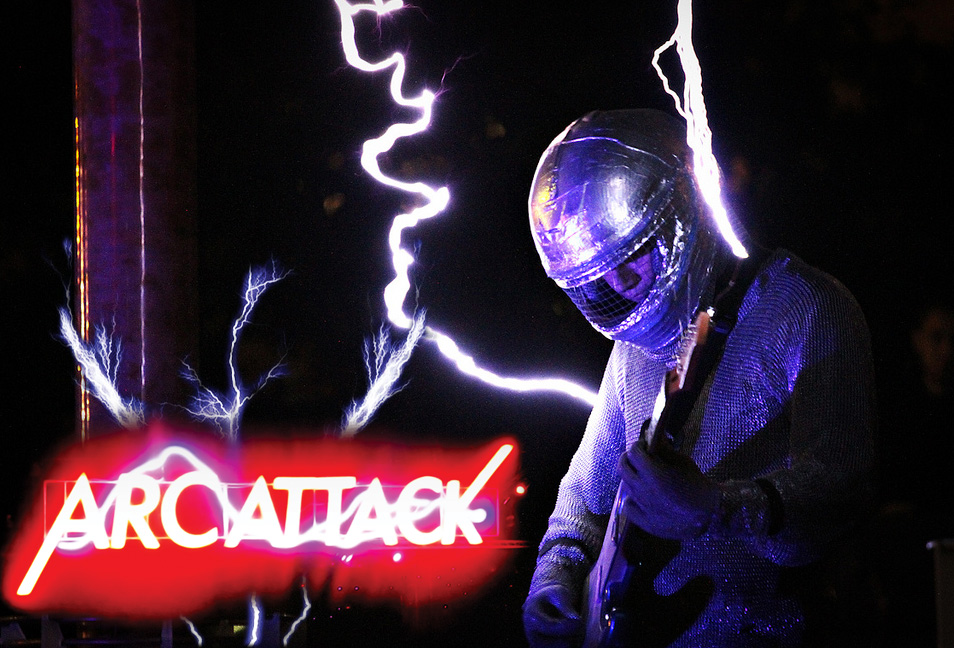 A photo of man playing guitar in a faraday cage with lightning stricking him. Neon text reads "ArcAttack."