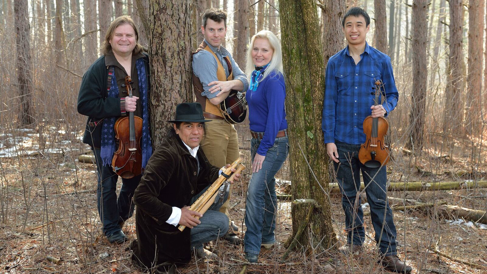 The group is pictured holding their instruments in a forest