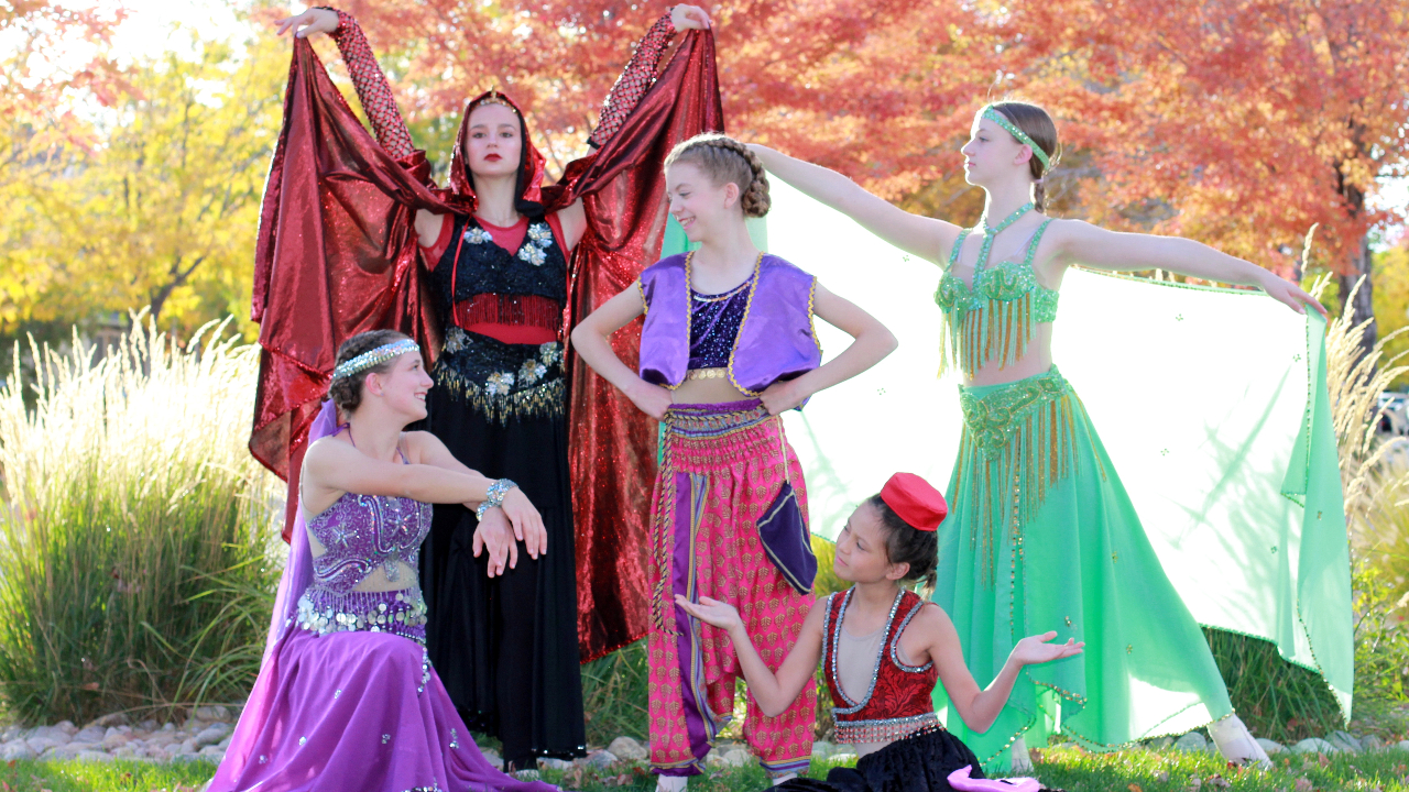 This image depicts ballet dancers dressed in colorful Arabian costumes in an autumnal setting.